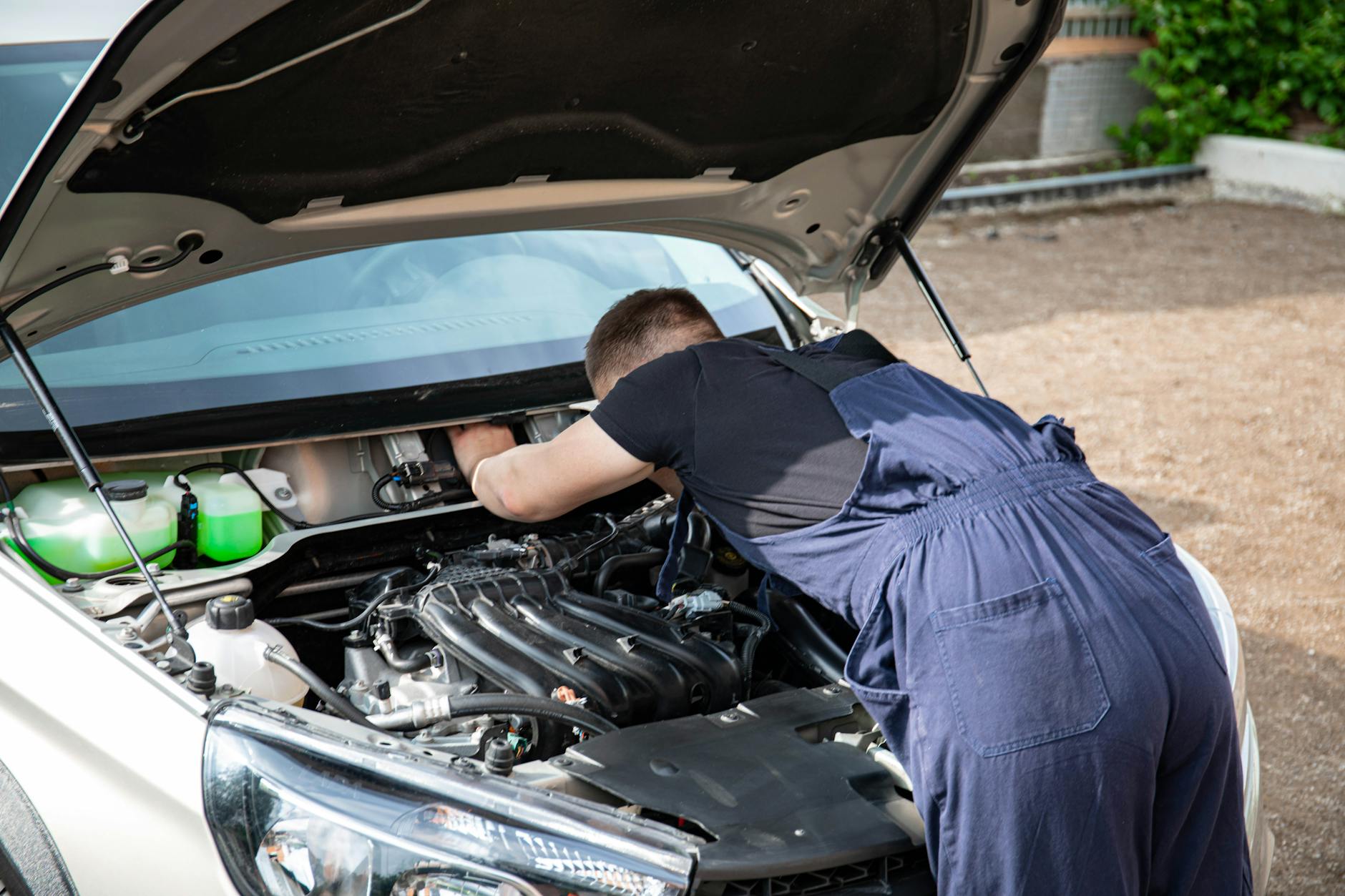 Mechanik naprawiający silnik Chevroleta Aveo w świetle dziennym
