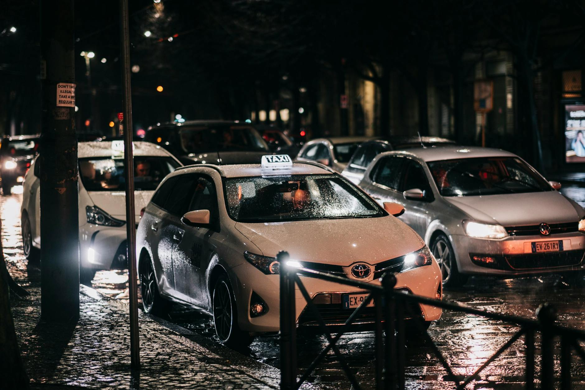 Nocna ulica dużego miasta z taksówkami na mokrym, oświetlonym asfalcie