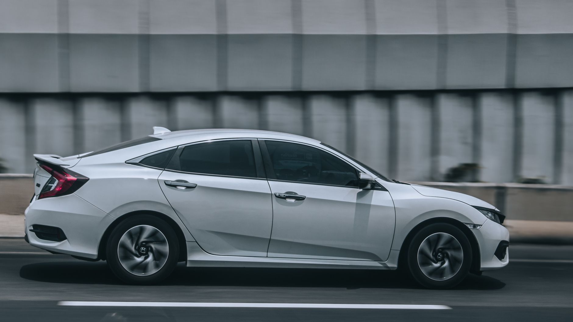 Biała Dacia jedzie po miejskiej ulicy, ujęcie w ruchu