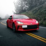 Czerwona sportowa Mazda jedzie krętą drogą we mgle