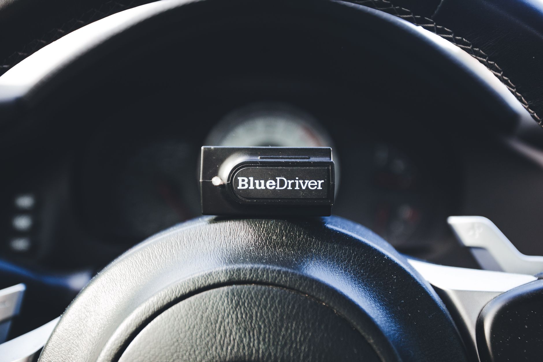Interfejs OBD BlueDriver leżący na kierownicy samochodu