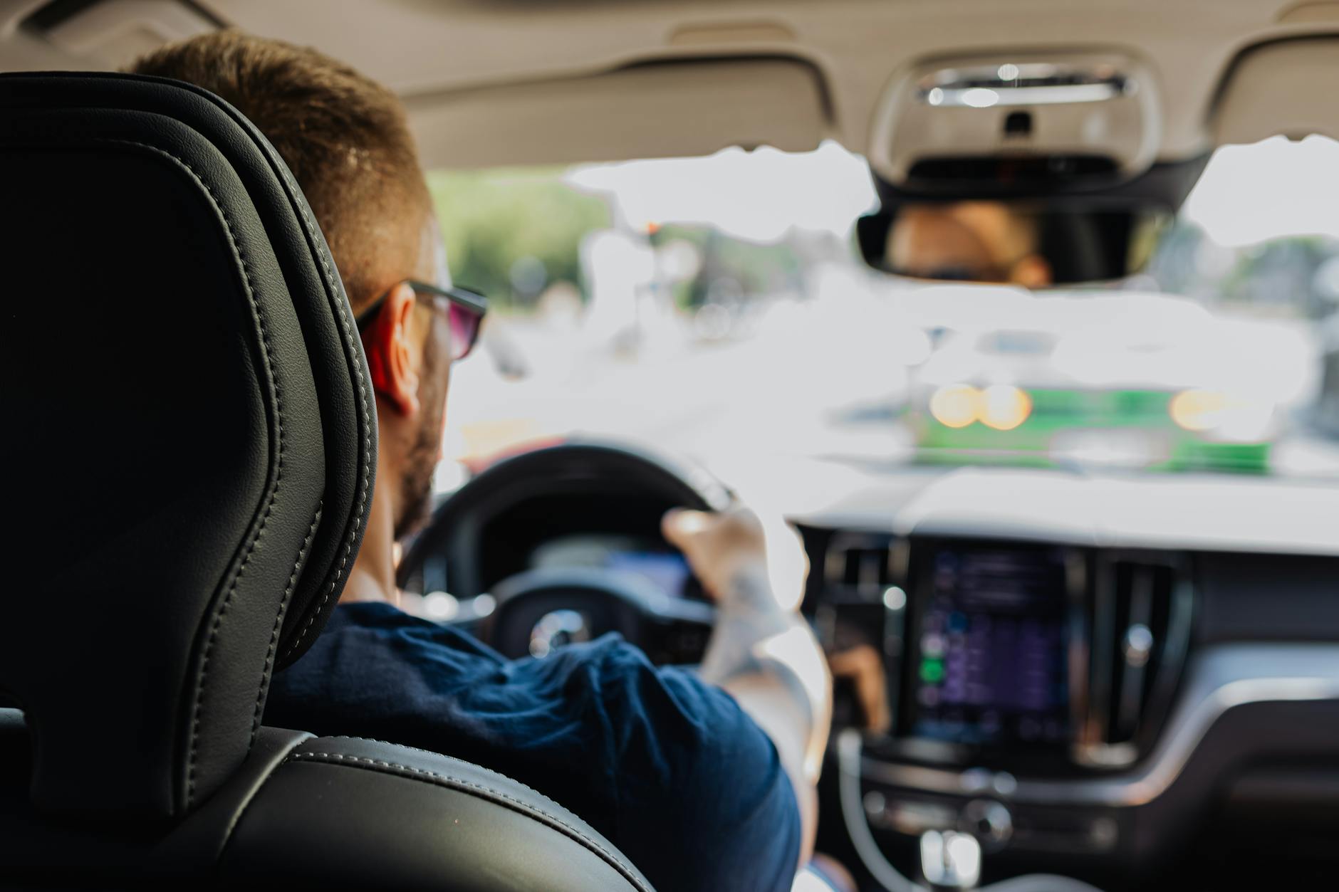 Kierowca prowadzący nowoczesne auto w ruchu miejskim zza fotela