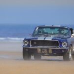 Klasyczny Ford Mustang GT350 jadący po piaszczystej plaży nad morzem