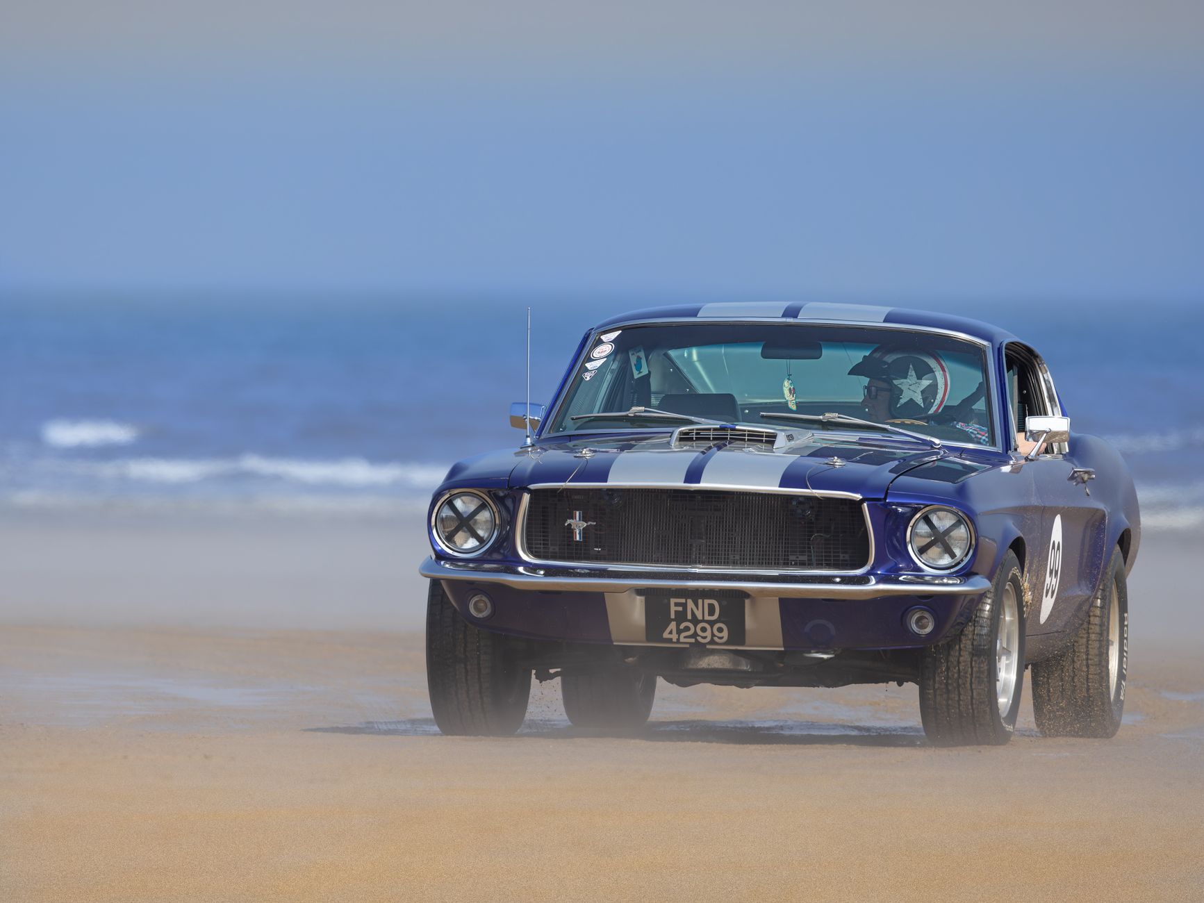Klasyczny Ford Mustang GT350 jadący po piaszczystej plaży nad morzem