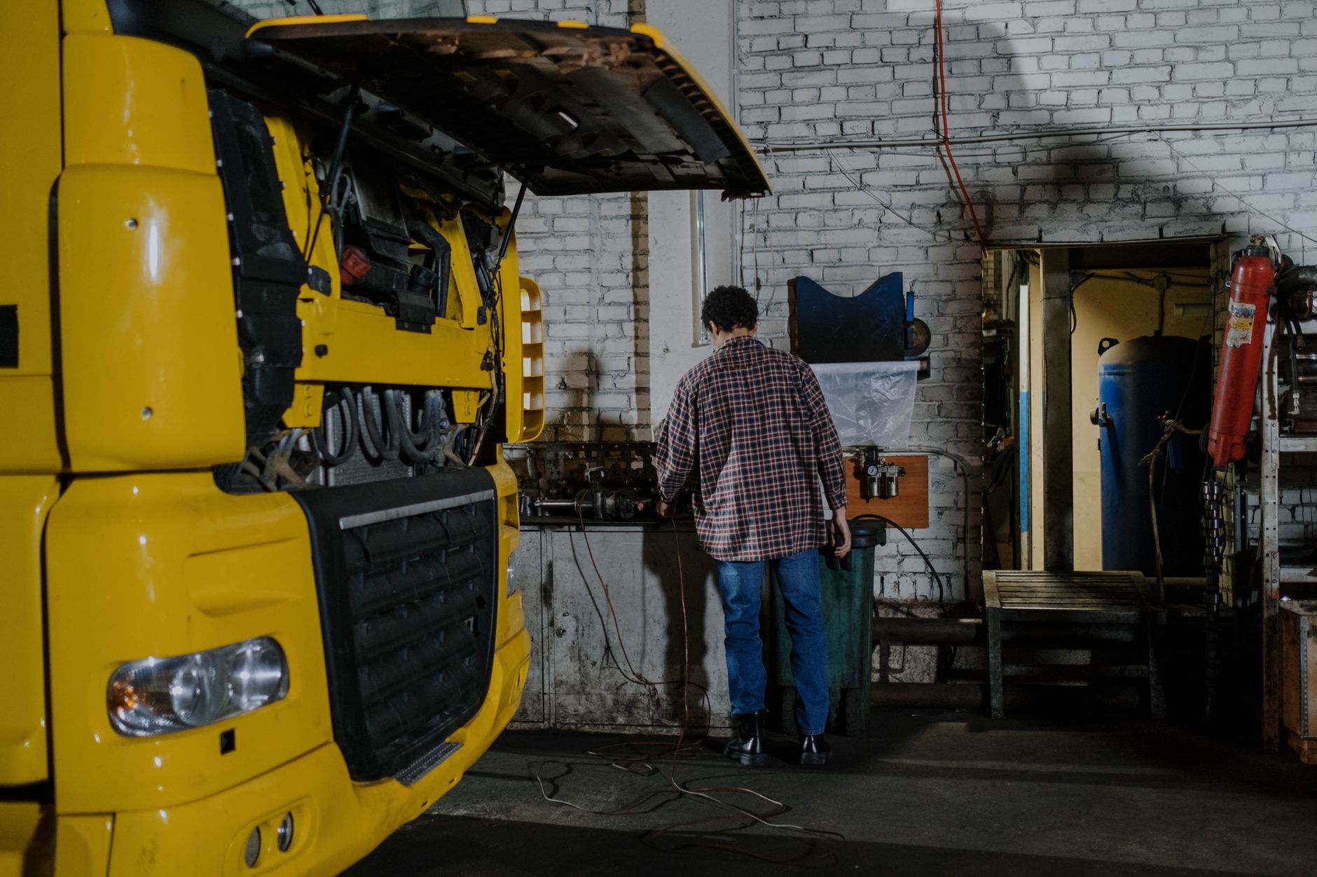 Mechanik naprawiający silnik żółtej ciężarówki w warsztacie