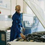 Mechanik w niebieskim uniformie sprawdza silnik Mitsubishi w warsztacie
