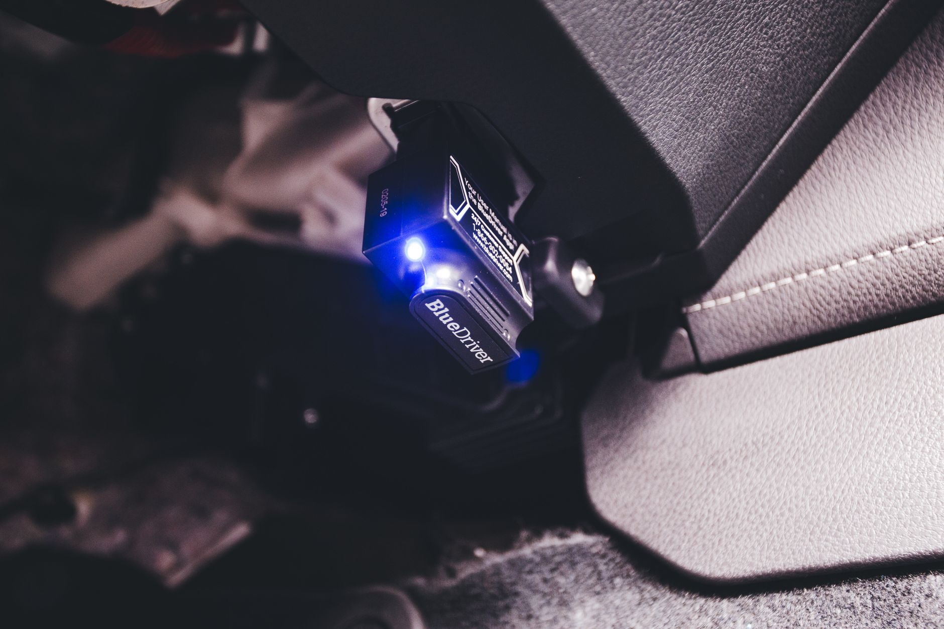 Niebieski interfejs Bluetooth OBD podłączony w kokpicie Mazdy