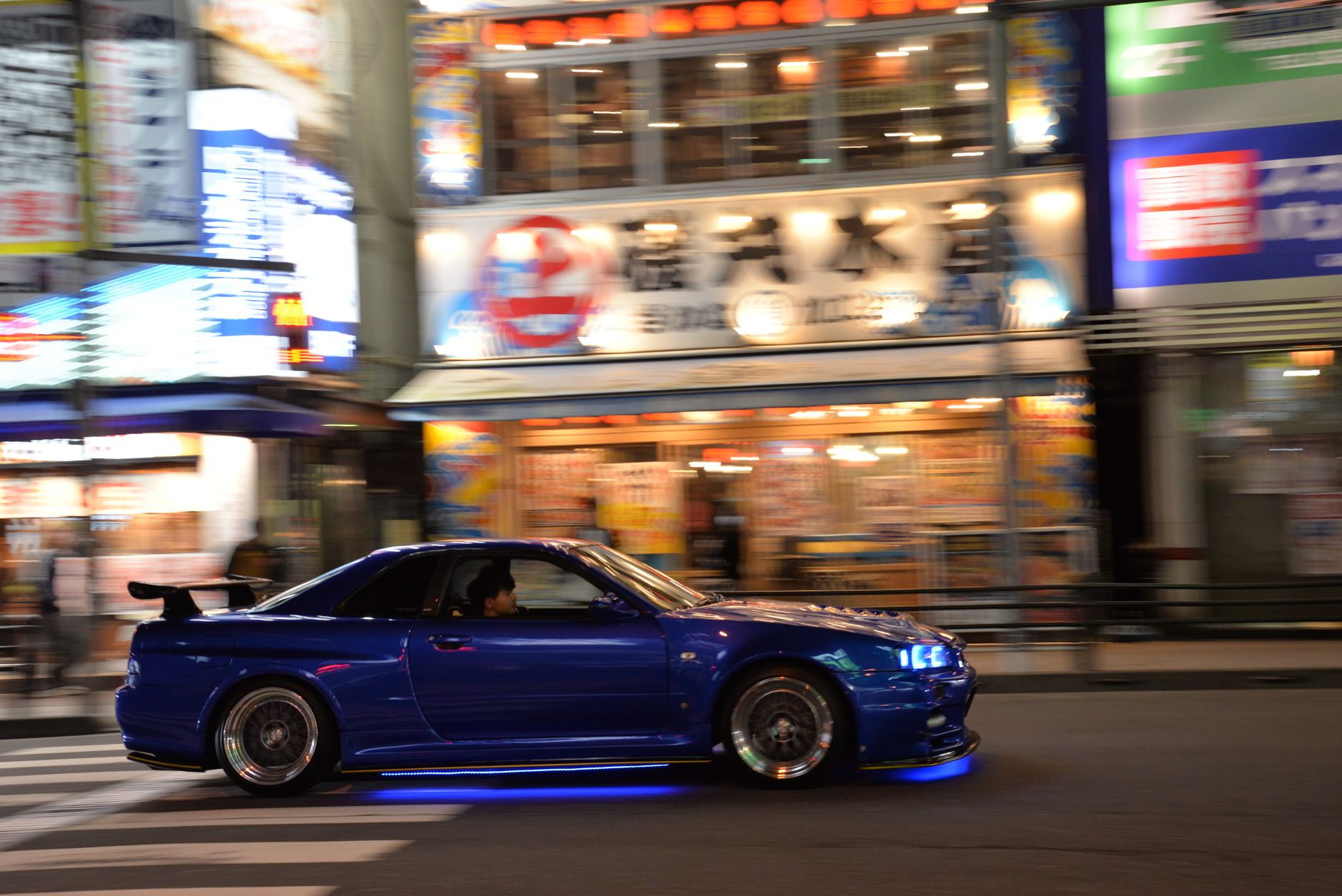 Niebieskie Subaru BRZ jedzie nocą po oświetlonych ulicach Tokio