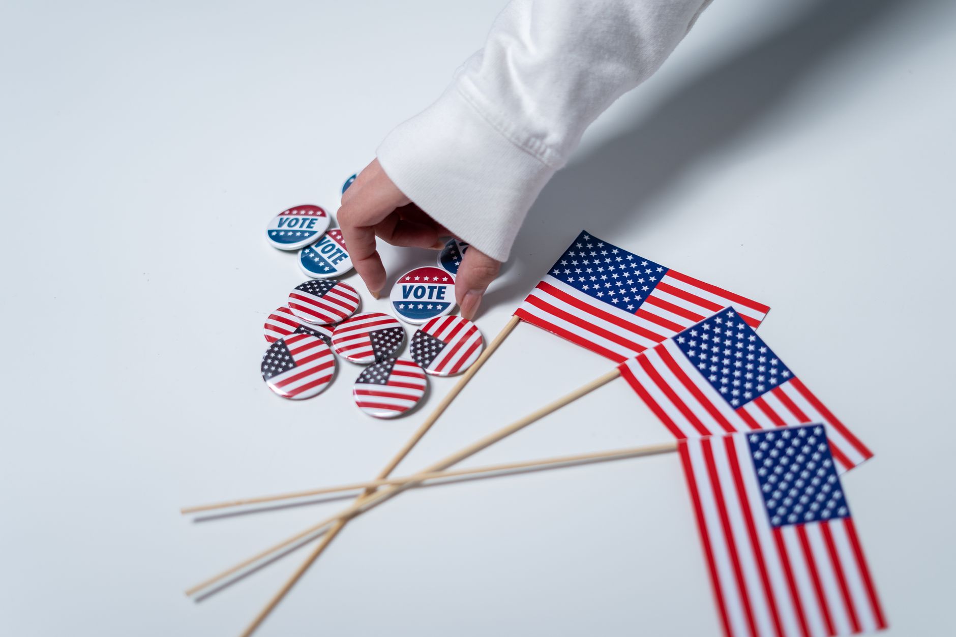 Dłoń sięgająca do przycisków do głosowania obok flag USA Dłoń sięgająca do przycisków do głosowania obok flag USA
